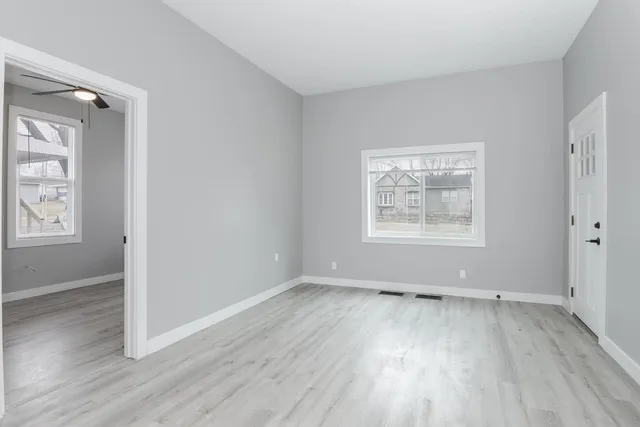 an empty room with wooden floor and windows