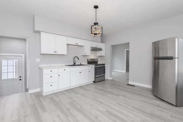 a kitchen with stainless steel appliances a stove a refrigerator and white cabinets