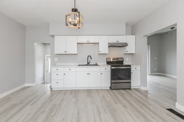a kitchen with stainless steel appliances a white stove top oven cabinets and a wooden floor