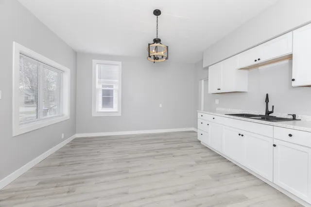 a kitchen with granite countertop a stove a sink and white cabinets with wooden floor