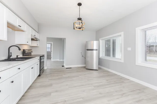 a kitchen with granite countertop white cabinets and refrigerator