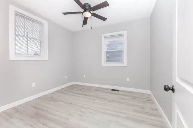 an empty room with windows and fan