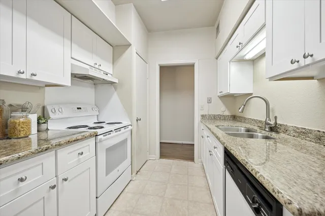 a kitchen with granite countertop a sink stove and cabinets