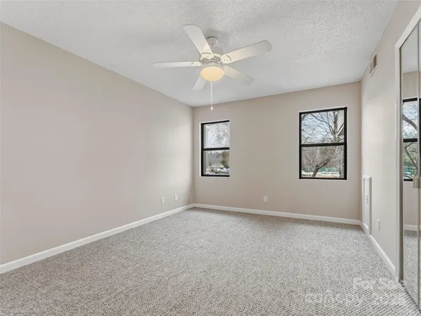 an empty room with windows and fan