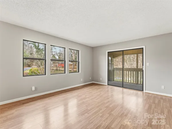 a view of an empty room with a window and wooden floor