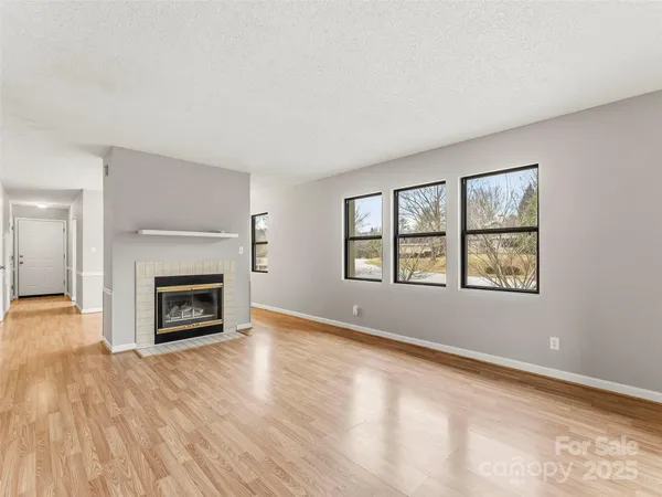 an empty room with windows and fireplace