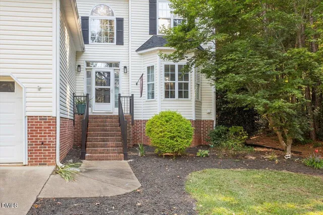 a view of a house with a yard and potted plants