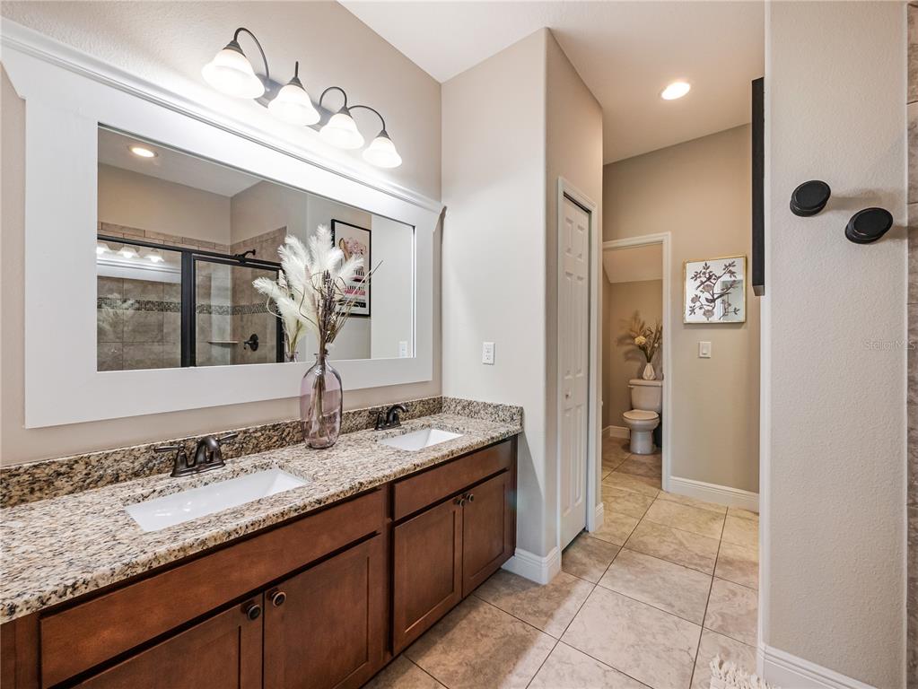 8416 Magnificent Road Groveland, FL 34736 - Photo 15 of 28 a bathroom with a granite countertop sink a mirror and a shower