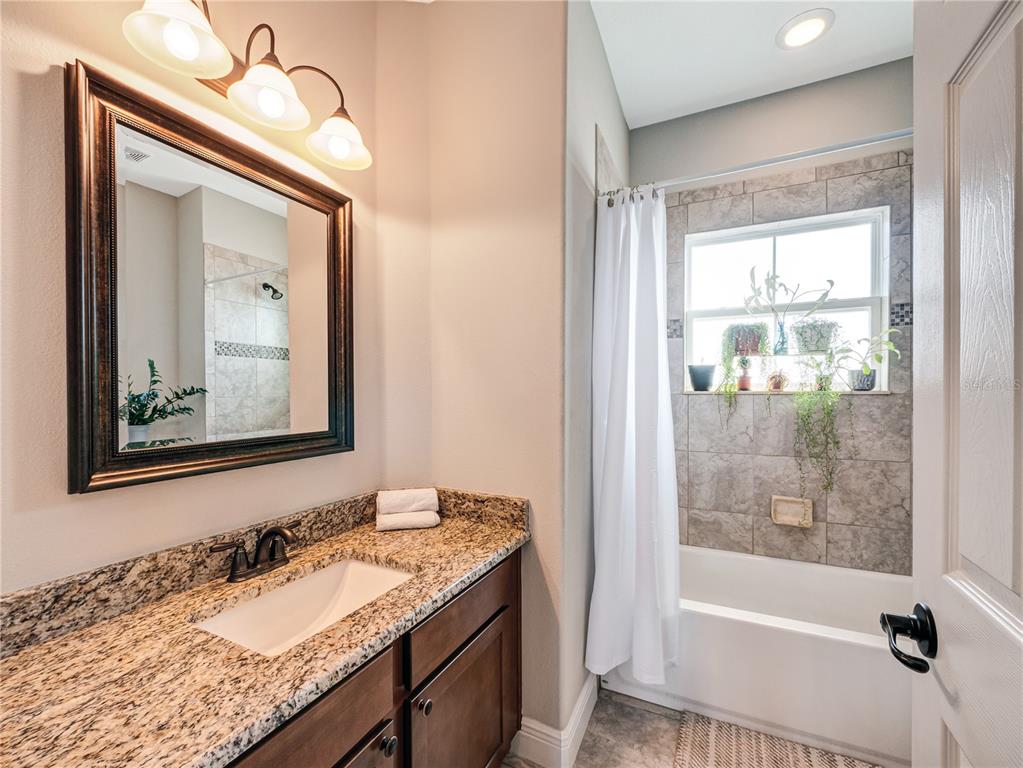 8416 Magnificent Road Groveland, FL 34736 - Photo 23 of 28 a bathroom with a granite countertop sink a mirror and a bathtub