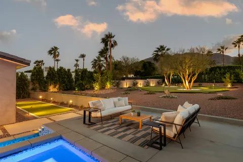 a view of swimming pool with outdoor seating and trees in the background