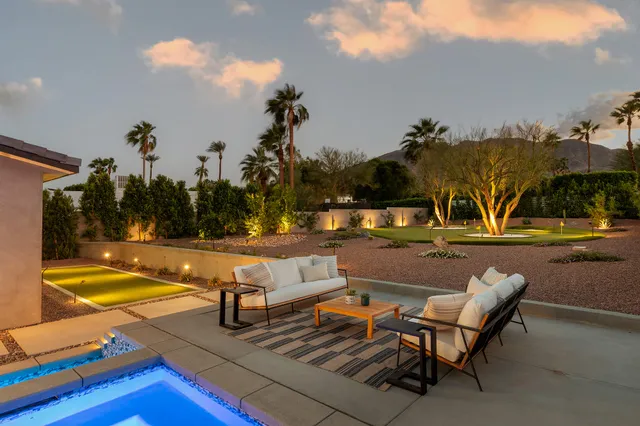 a view of swimming pool with outdoor seating and trees in the background