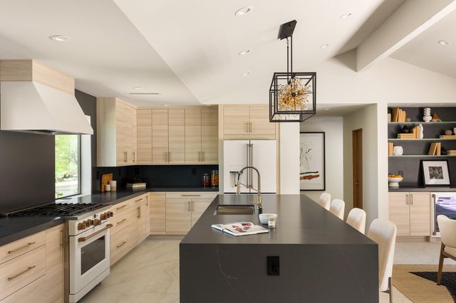 a kitchen with stainless steel appliances a sink dishwasher a stove a microwave oven with white cabinets and wooden floor