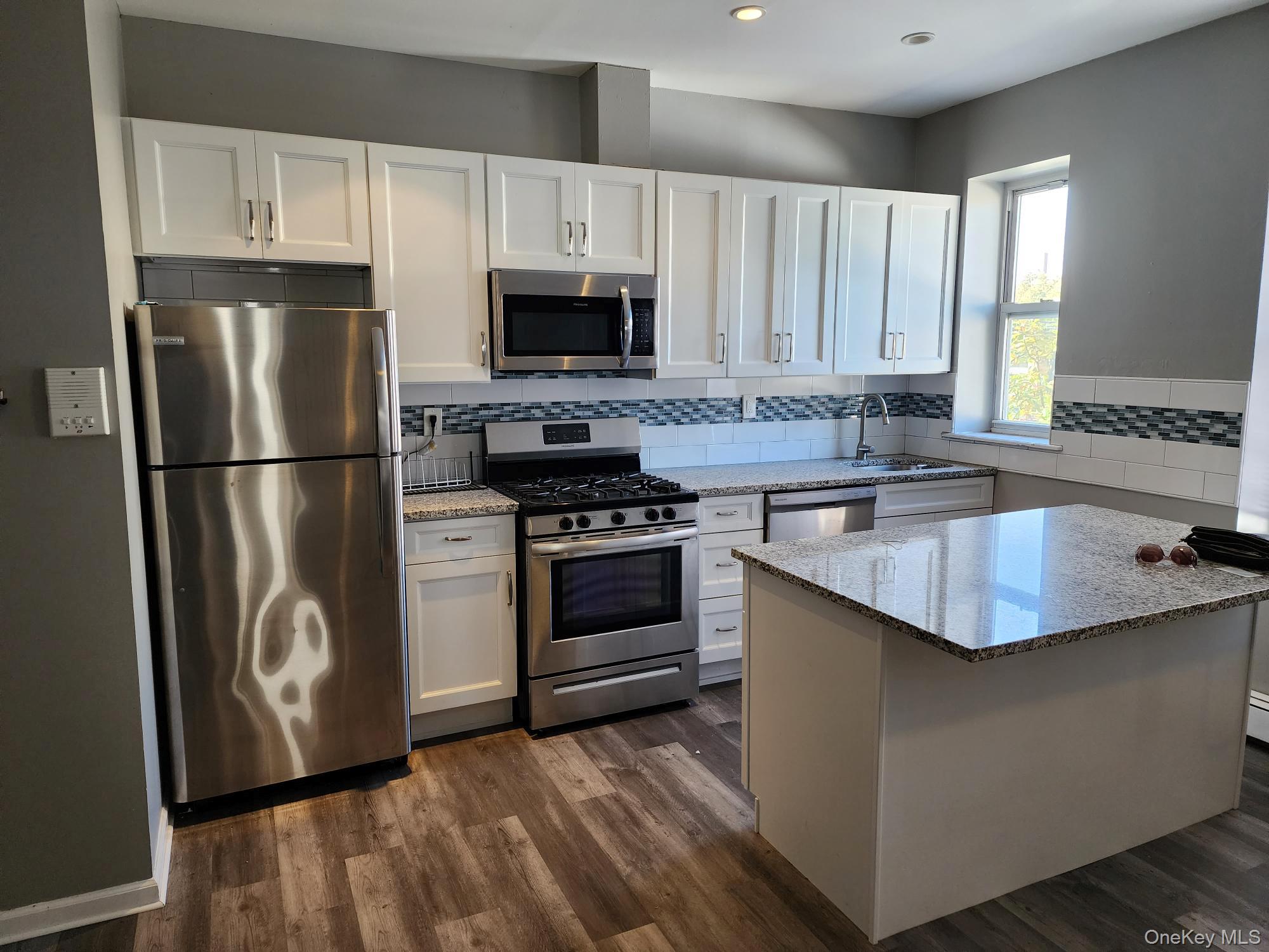 45-01 Ditmars Boulevard, Unit 2R Queens, NY 11105 - Photo 5 of 13 a kitchen with stainless steel appliances granite countertop a refrigerator stove a sink and a microwave