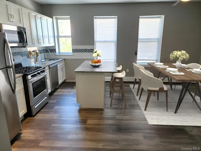 a kitchen with stainless steel appliances wooden floor dining table and chairs