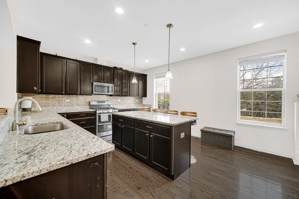 a kitchen with stainless steel appliances granite countertop a sink a stove and a wooden floors