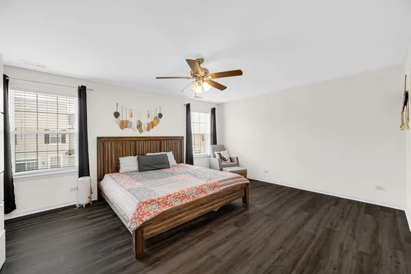 a bedroom with a bed and a large window with wooden floor