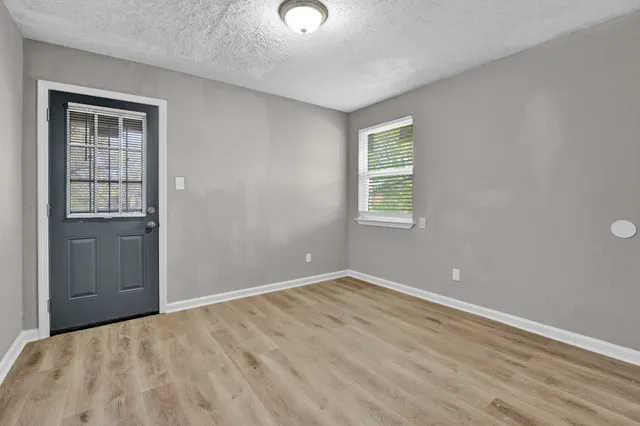 a view of a wooden house with a small yard and large tree