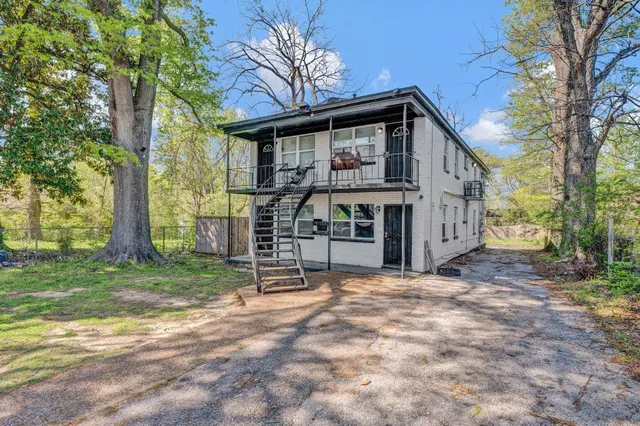a view of house with outdoor seating and covered with trees