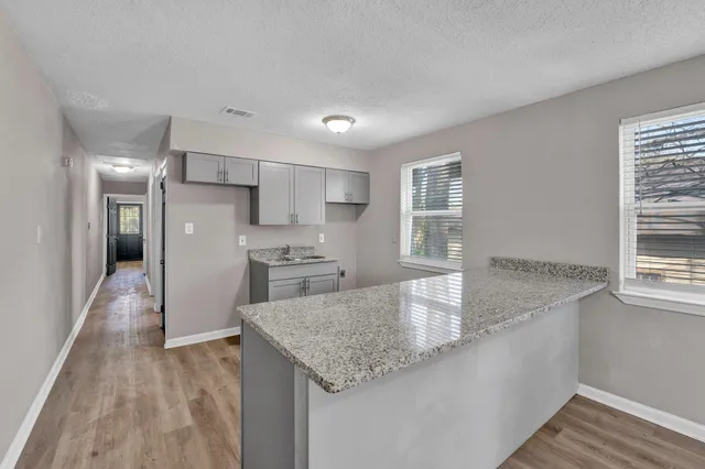 a kitchen with stainless steel appliances granite countertop a sink dishwasher and a refrigerator with wooden floor