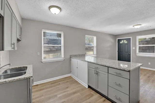a kitchen with white cabinets and window