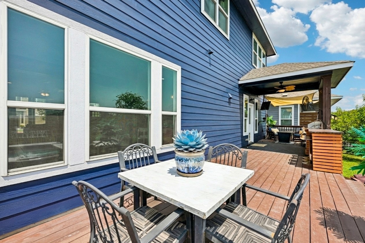 1297 Harwell Loop Kyle, TX 78640 - Photo 33 of 39 A spacious wooden deck extends from the vibrant blue home, offering a perfect spot for outdoor dining.