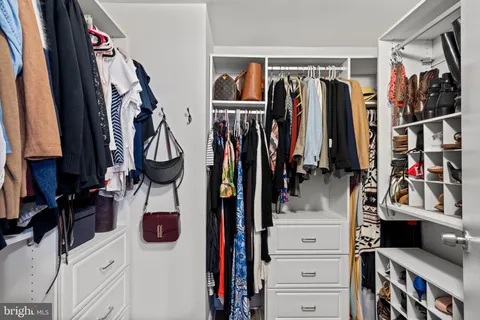 a view of walk in closet with clothes and shoes