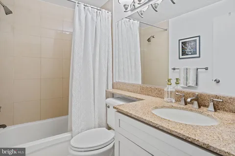 a bathroom with a granite countertop sink toilet and shower