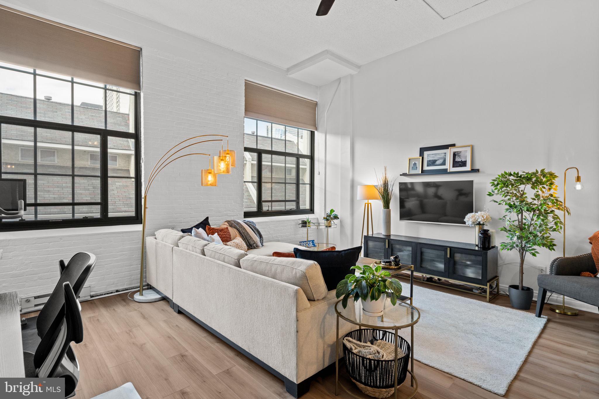 2429 Locust Street, Unit 314 Philadelphia, PA 19103 - Photo 5 of 21 a living room with furniture a flat screen tv and a floor to ceiling window