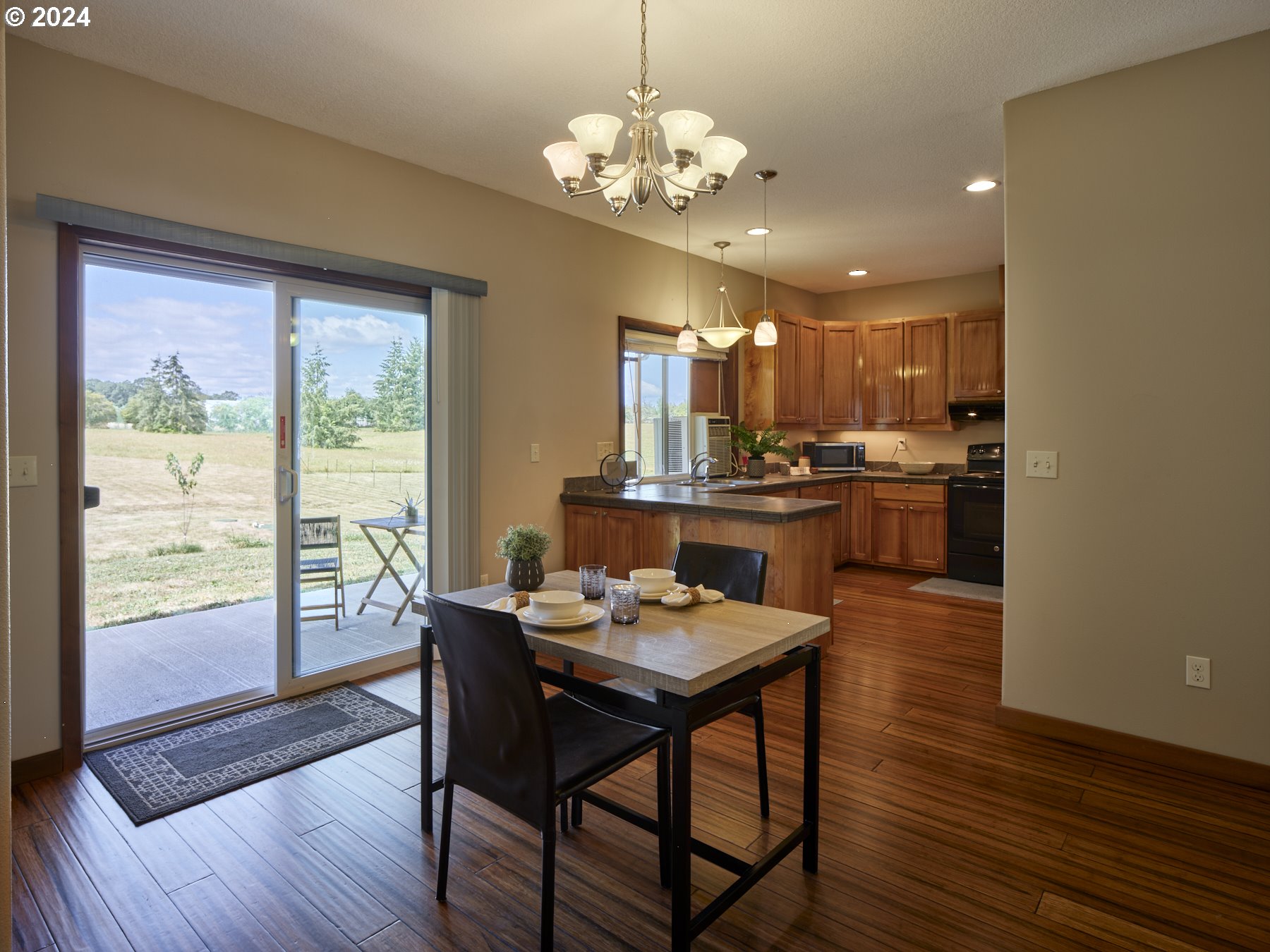29902 Northwest 51st Avenue Ridgefield, WA 98642 - Photo 10 of 46 a dining room with wooden floor a chandelier a wooden table and chairs