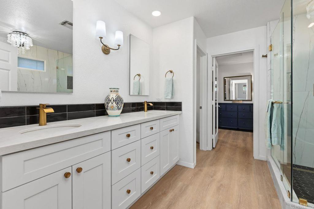 7039 Whitewater Street Carlsbad, CA 92011 - Photo 18 of 65 a spacious bathroom with double vanity a mirror a lamp and a bathtub
