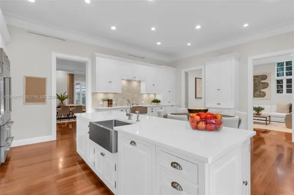 a kitchen that has a lot of cabinets a sink and wooden floor