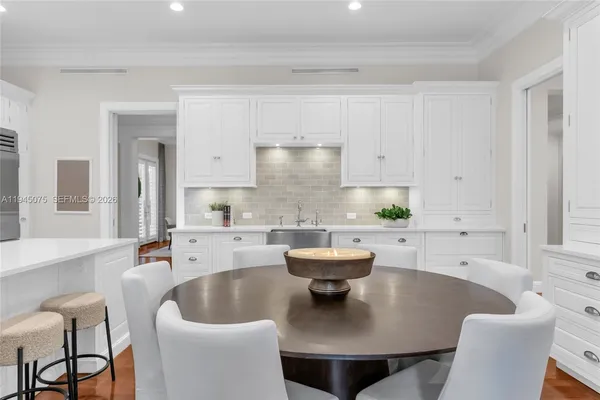a large white kitchen with a white table and chairs