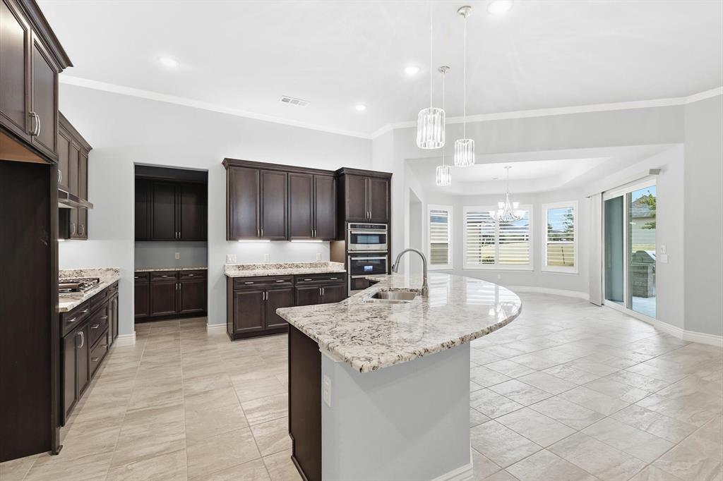 8813 Basanite Avenue Denton, TX 76207 - Photo 12 of 40 a large kitchen with granite countertop a large counter top stainless steel appliances and cabinets