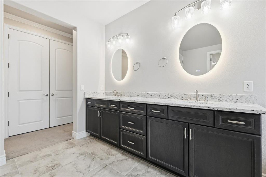 8813 Basanite Avenue Denton, TX 76207 - Photo 20 of 40 a bathroom with a granite countertop double vanity sink and a mirror