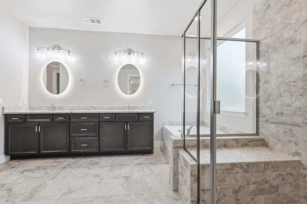 8813 Basanite Avenue Denton, TX 76207 - Photo 21 of 40 a bathroom with a granite countertop sink a mirror and a shower