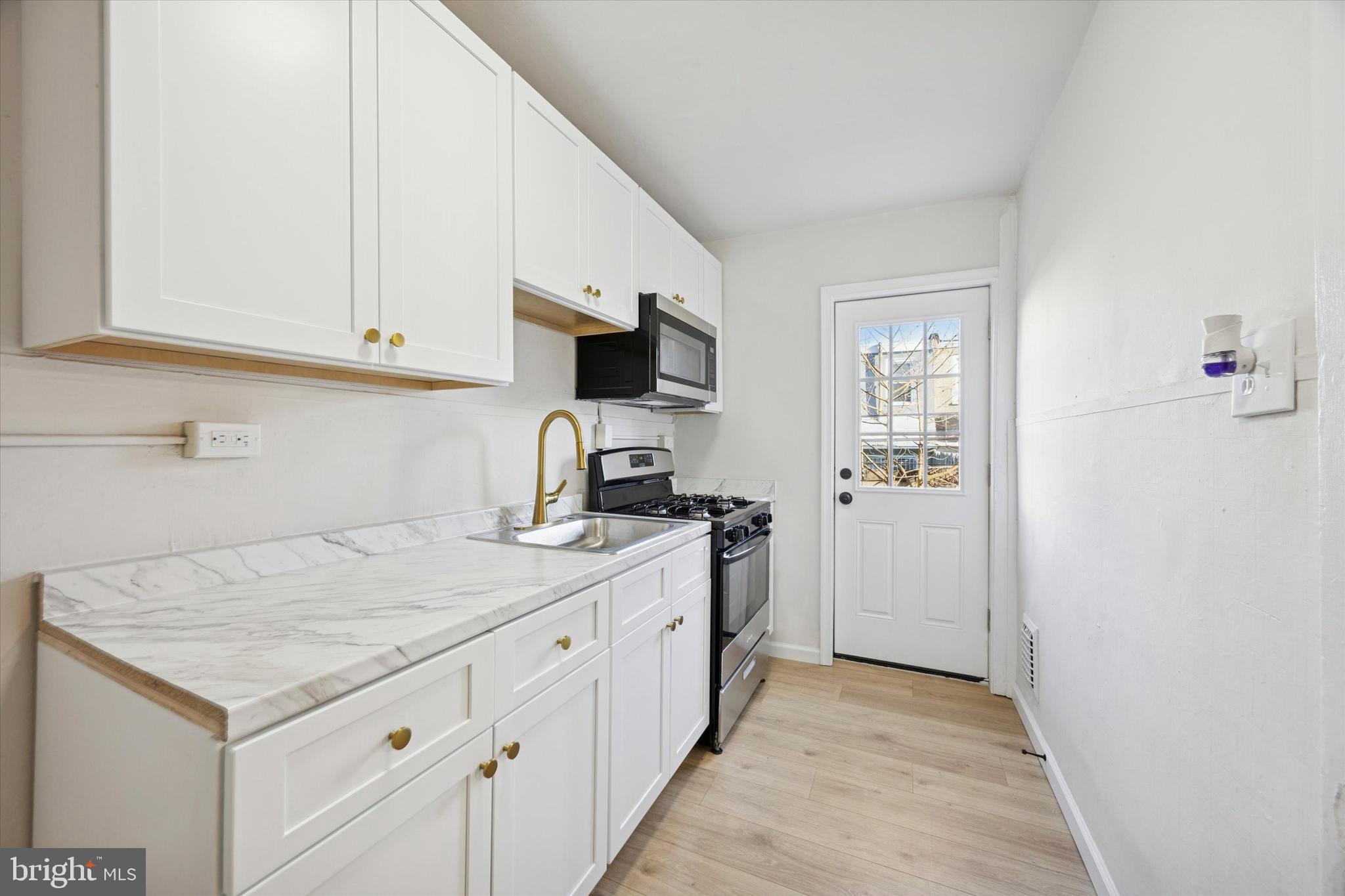 2537 South Millick Street Philadelphia, PA 19142 - Photo 7 of 15 a kitchen with a sink stove and cabinets