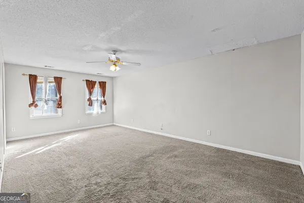 an empty room with windows and fan