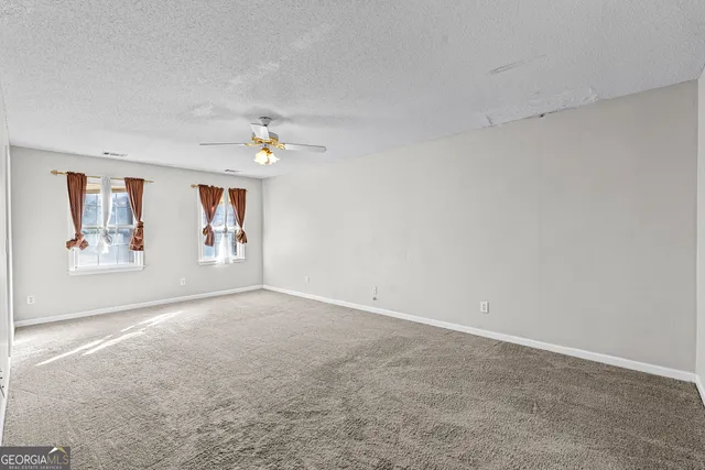 an empty room with windows and fan