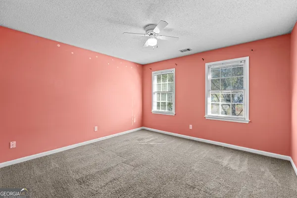 an empty room with window and ceiling fan