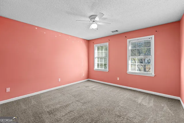 an empty room with window and ceiling fan