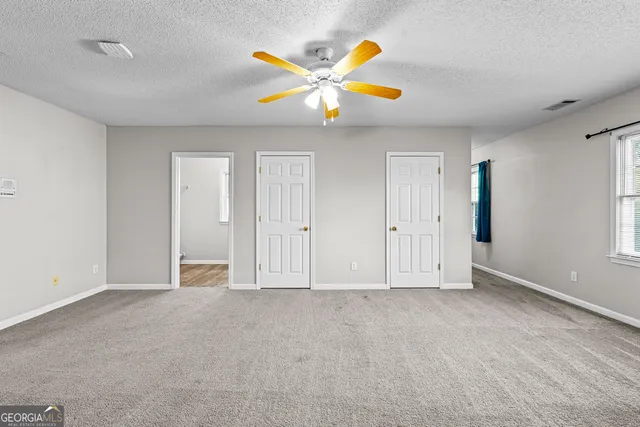 an empty room with closet and a chandelier fan