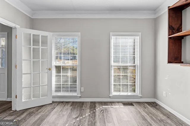 an empty room with wooden floor and windows