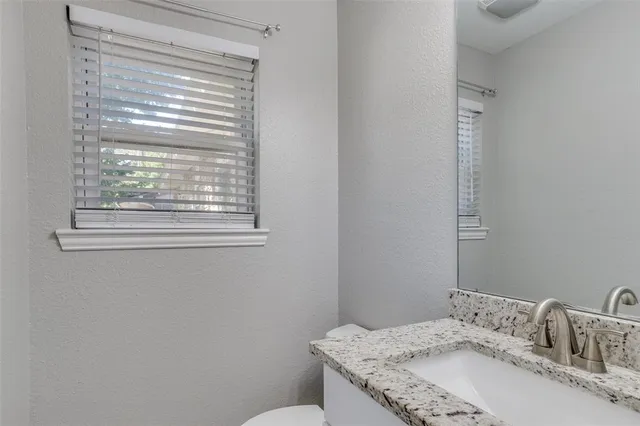 a bathroom with a granite countertop sink a toilet and a mirror
