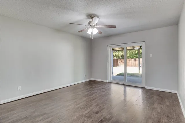 an empty room with wooden floor fan and windows