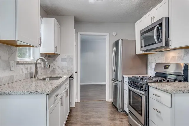 a kitchen with granite countertop a sink stove and refrigerator