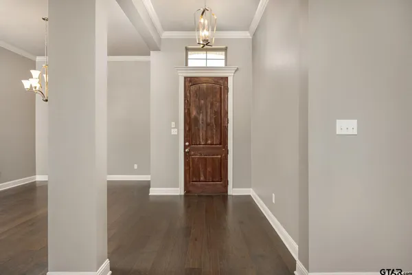 an empty room with wooden floor closet and chandelier