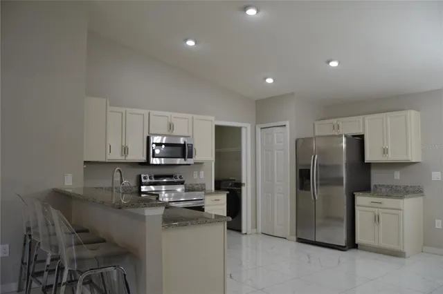 a kitchen with stainless steel appliances granite countertop a refrigerator a stove a sink and a microwave