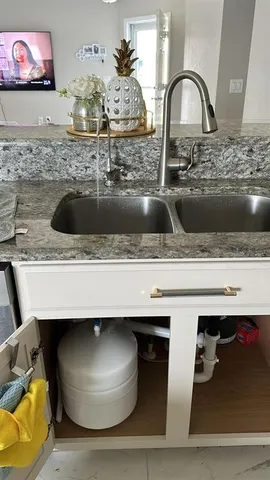 a kitchen with a sink and a stove with wooden floor