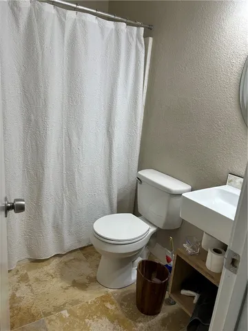 a bathroom with a toilet and a shower curtain