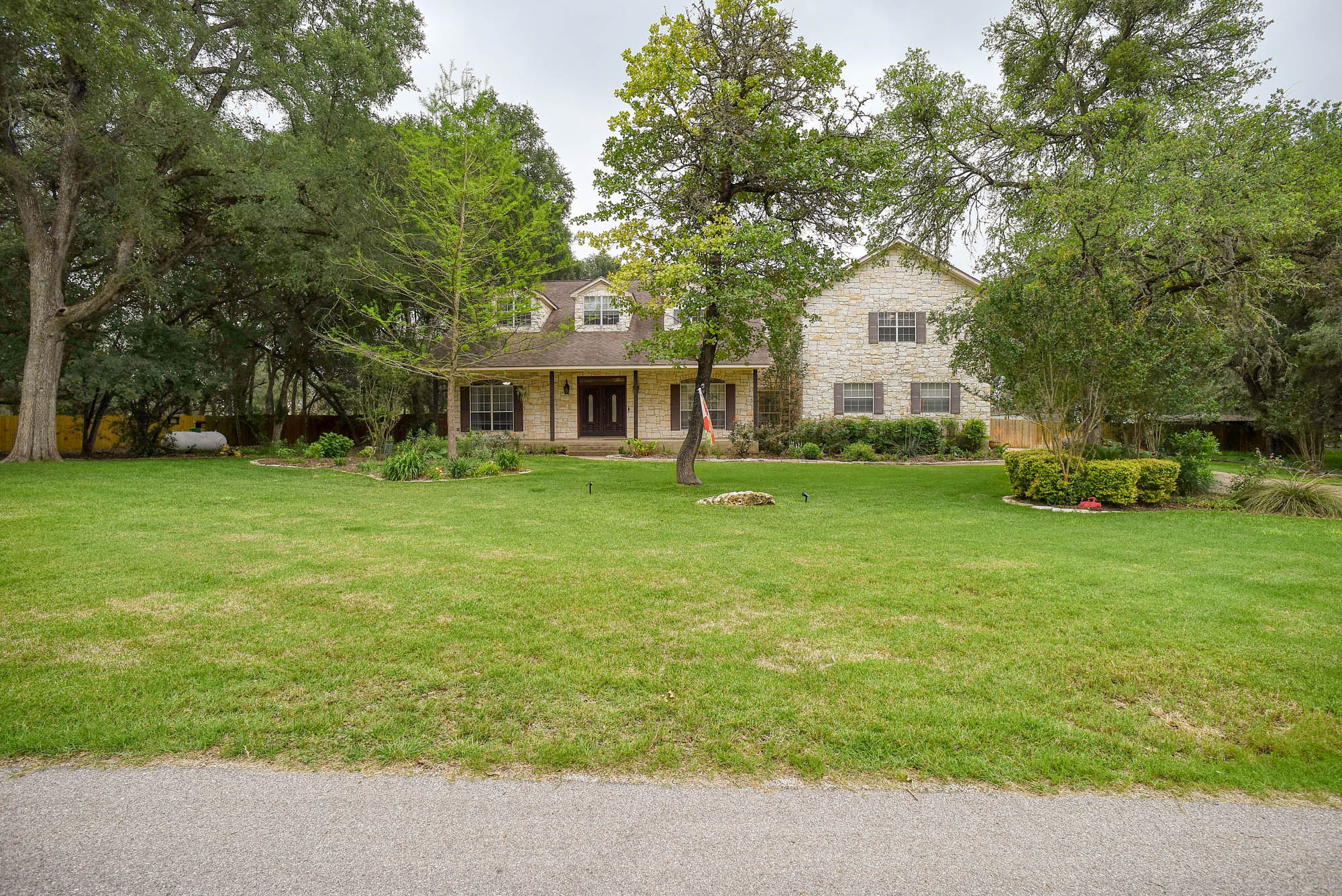 147 Spring Meadow Road Bastrop, TX 78602 - Photo 2 of 40 a front view of a house with a garden and trees